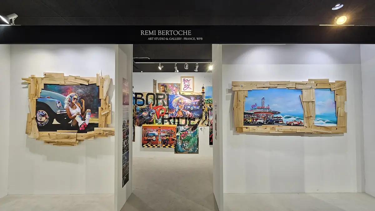 Accrochage de peintures dans une galerie, entre cadres en bois et compositions colorées
