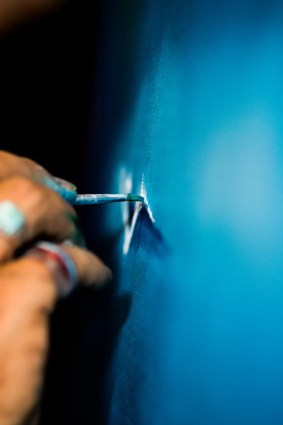 The artist’s brush working into a blue canvas